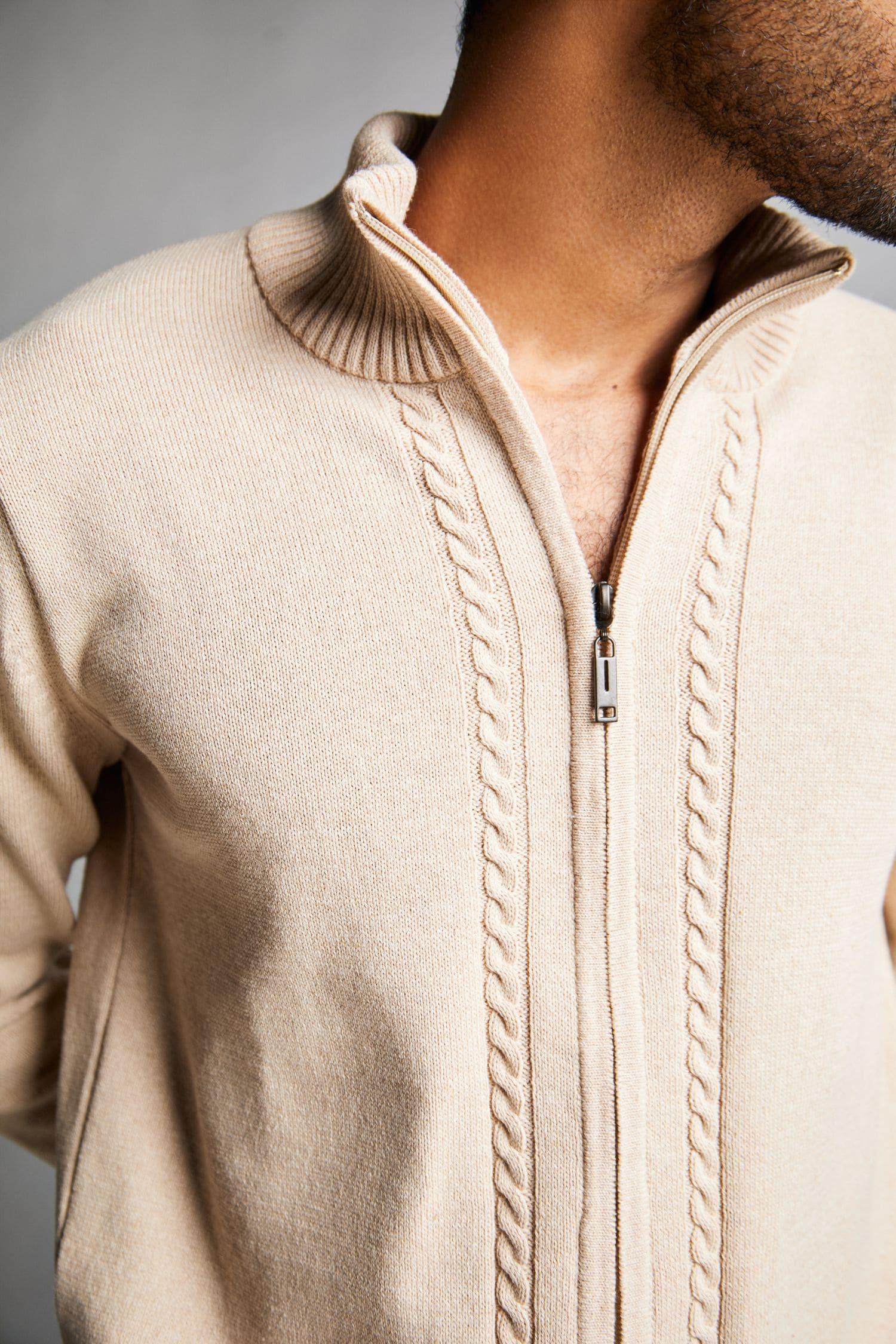 Detalle de suéter beige para hombre en tejido de punto con cremallera y cuello alto